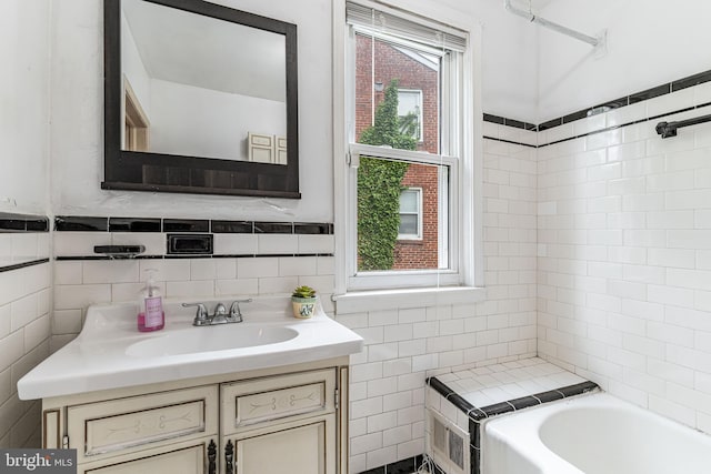 bathroom featuring tile walls, a bath, and vanity