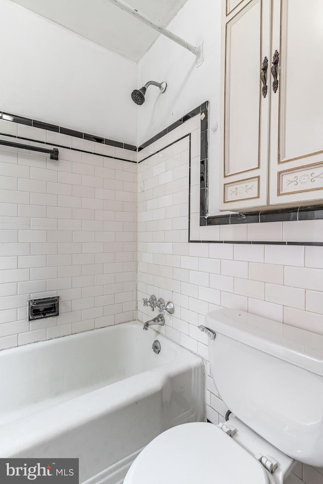 bathroom featuring tile walls, toilet, and shower / washtub combination