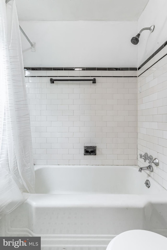 bathroom featuring toilet and shower / bathtub combination with curtain