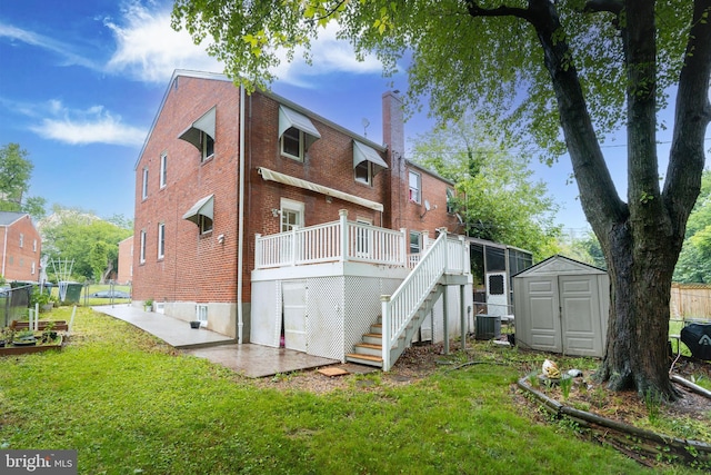 rear view of house featuring a shed, brick siding, a wooden deck, a chimney, and stairs