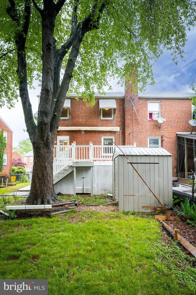 rear view of house featuring brick siding, a storage unit, an outbuilding, and a lawn