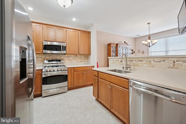 kitchen featuring tasteful backsplash, appliances with stainless steel finishes, light countertops, a sink, and light tile patterned flooring
