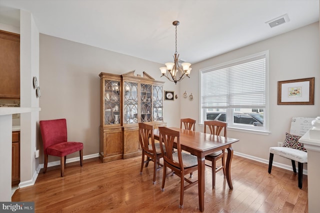 dining room with baseboards, light wood-type flooring, and an inviting chandelier