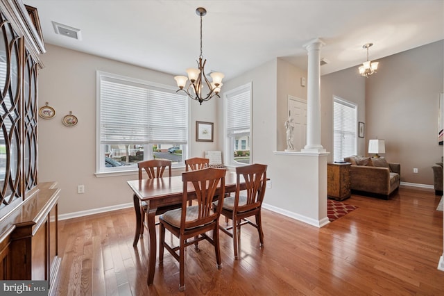 dining space featuring wood finished floors, decorative columns, a chandelier, and baseboards
