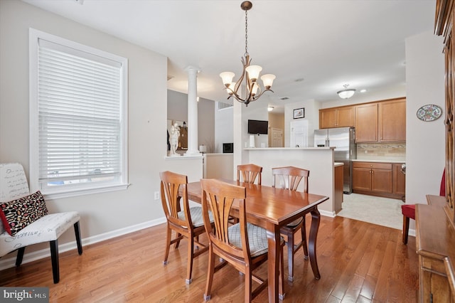 dining space featuring light wood-style floors, a notable chandelier, and baseboards