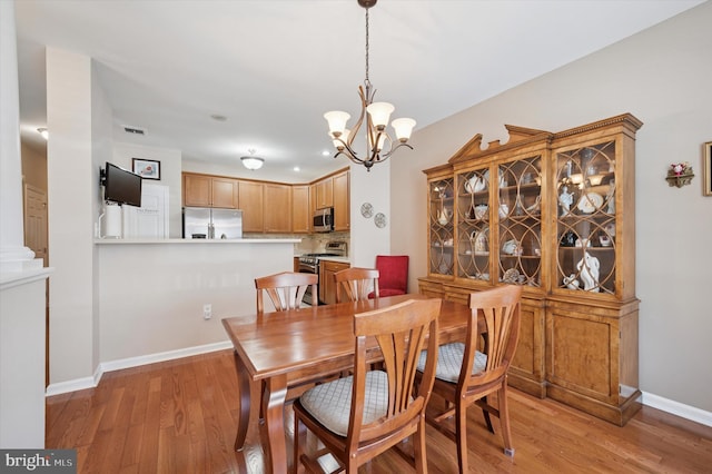 dining room featuring visible vents, light wood-style flooring, a chandelier, and baseboards