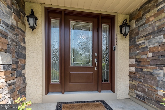 view of exterior entry featuring stucco siding and a porch