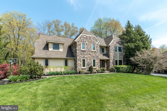 view of front of home with a shingled roof, a front lawn, stucco siding, and stone siding