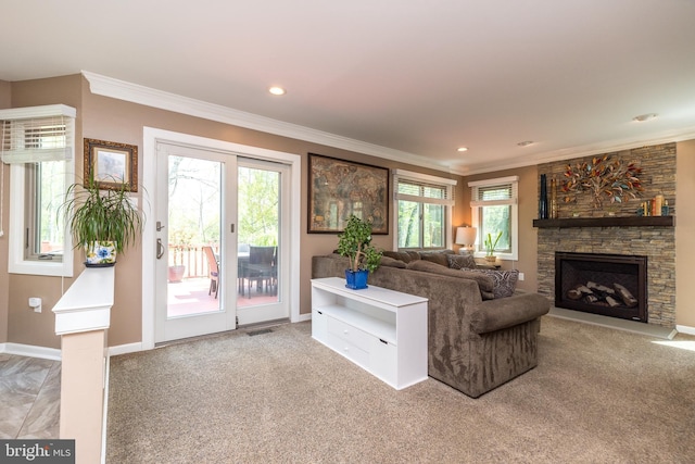 living area featuring crown molding, baseboards, a stone fireplace, and a healthy amount of sunlight