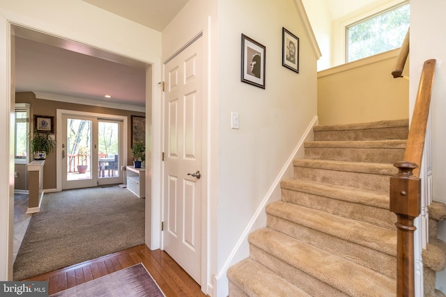 stairs featuring baseboards, ornamental molding, a wealth of natural light, and hardwood / wood-style floors