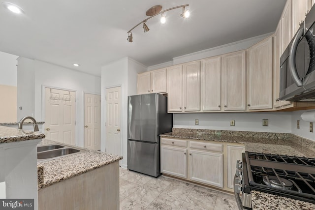 kitchen featuring light stone counters, a sink, light brown cabinetry, and stainless steel appliances