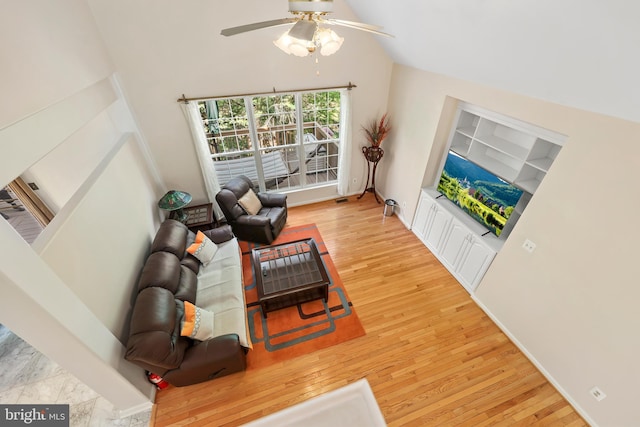 living area with ceiling fan, wood finished floors, and high vaulted ceiling