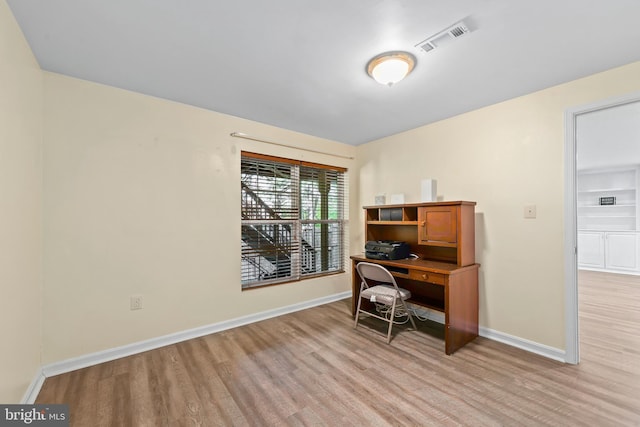 office area with baseboards, light wood finished floors, and visible vents