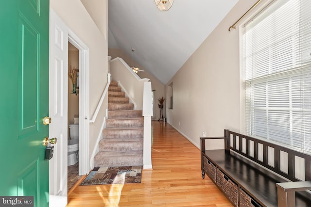 foyer entrance with stairs, baseboards, vaulted ceiling, and light wood-type flooring
