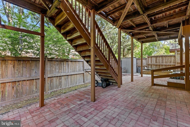 view of patio / terrace with stairs, a fenced backyard, a storage shed, and an outdoor structure