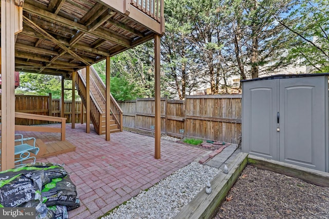 view of patio featuring stairway, an outbuilding, a shed, and a fenced backyard
