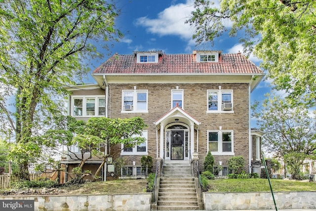 colonial home with brick siding, fence, and a tile roof