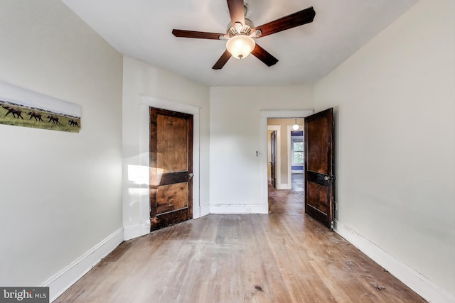 unfurnished living room featuring baseboards, a ceiling fan, and wood finished floors