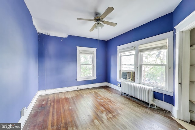 unfurnished room featuring visible vents, radiator, hardwood / wood-style floors, baseboards, and ceiling fan