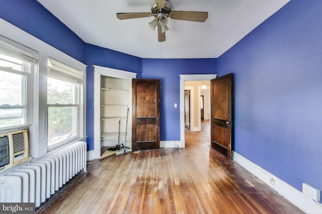unfurnished bedroom featuring baseboards, radiator, and hardwood / wood-style flooring
