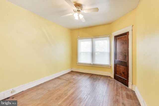 unfurnished room with wood-type flooring, a ceiling fan, and baseboards