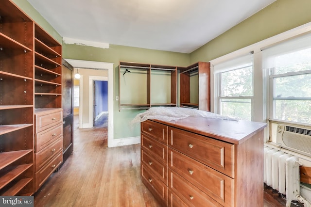 spacious closet featuring radiator heating unit, wood-type flooring, and cooling unit
