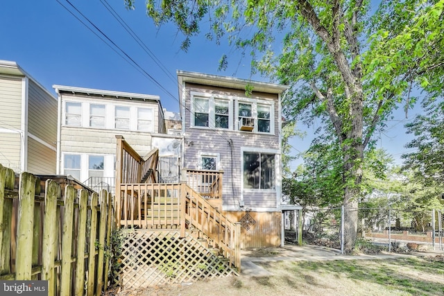 rear view of property with a deck, fence, and stairs