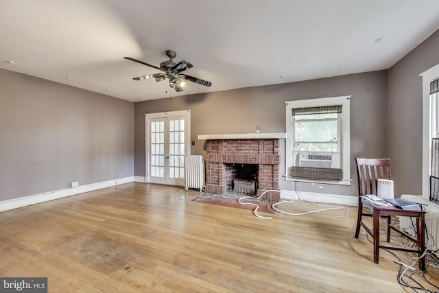 living room featuring radiator, ceiling fan, wood finished floors, and a healthy amount of sunlight