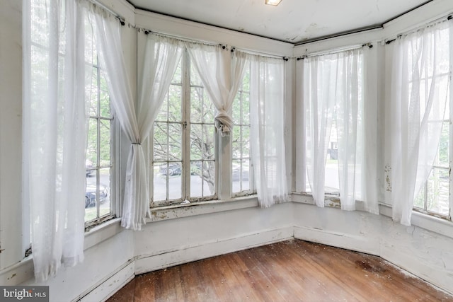 unfurnished sunroom with baseboards, a healthy amount of sunlight, and hardwood / wood-style floors