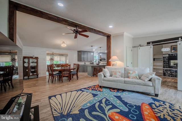 12 Woods Cir, Ocean View, DE 19970 - living room featuring a barn door, light wood finished floors, beamed ceiling, a ceiling fan, and crown molding