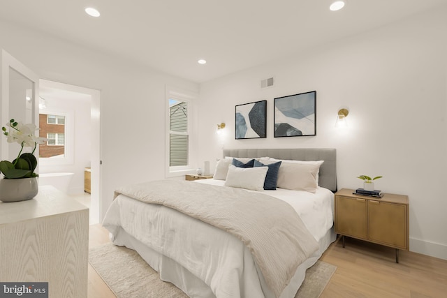 bedroom featuring ensuite bath, visible vents, light wood-type flooring, baseboards, and recessed lighting