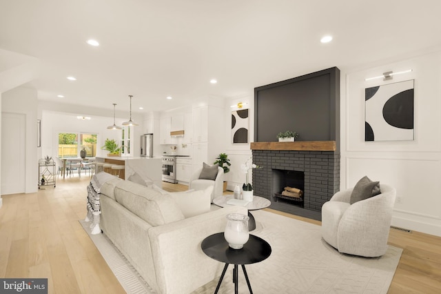 living area with recessed lighting, visible vents, light wood-style flooring, and a fireplace