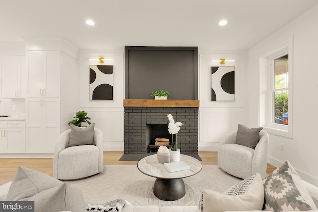 living area with a brick fireplace, recessed lighting, and light wood-style floors