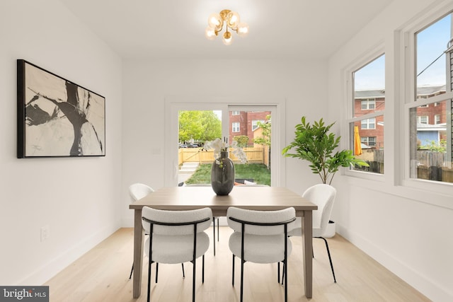 dining space with baseboards, a chandelier, and light wood finished floors