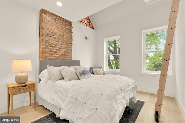 bedroom featuring baseboards, visible vents, light wood finished floors, and lofted ceiling