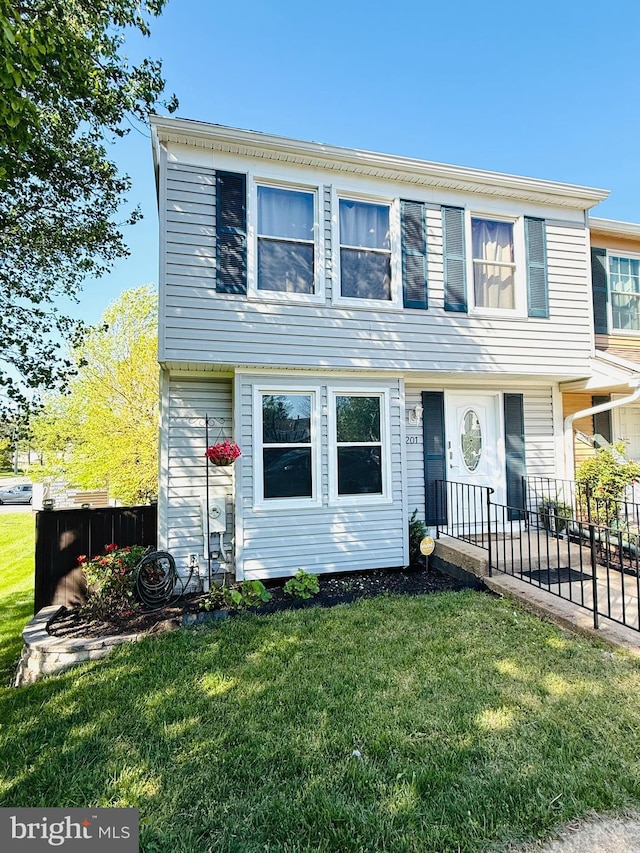 colonial inspired home with a front lawn and fence