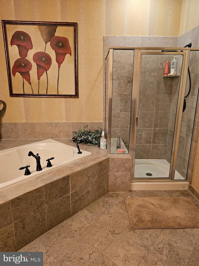 bathroom with a garden tub, a shower stall, and a textured wall