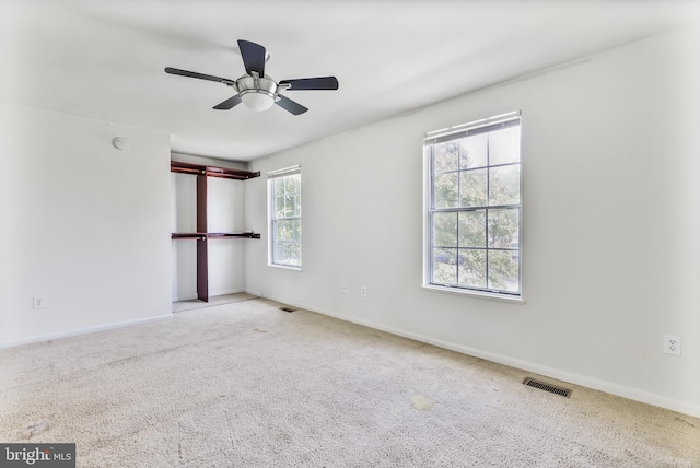 carpeted empty room featuring baseboards, a ceiling fan, and visible vents