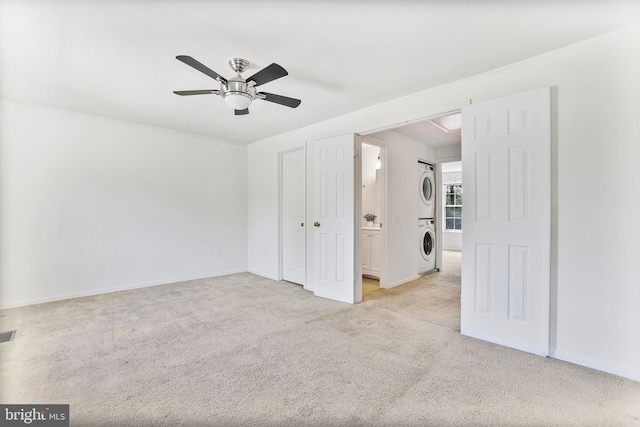 interior space featuring carpet flooring, baseboards, ceiling fan, and stacked washer and clothes dryer