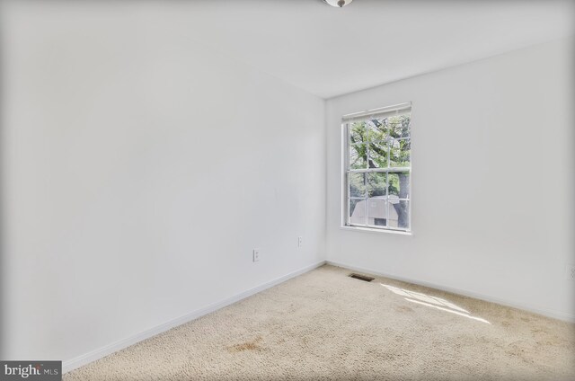 carpeted spare room with baseboards and visible vents