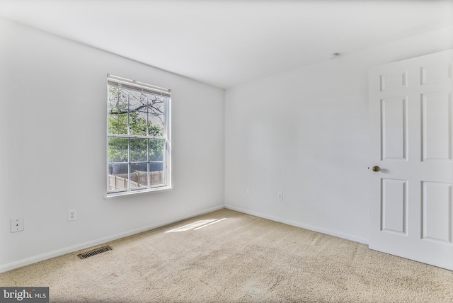 carpeted empty room featuring baseboards and visible vents