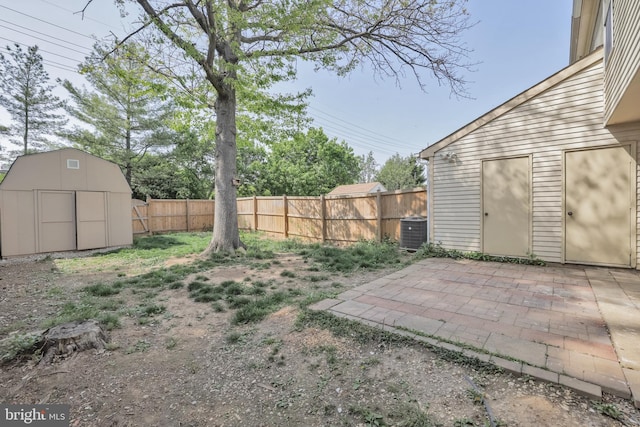 view of yard featuring an outbuilding, cooling unit, a fenced backyard, a storage unit, and a patio