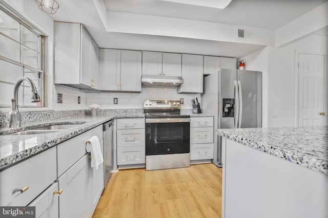 kitchen featuring visible vents, appliances with stainless steel finishes, light wood-type flooring, a sink, and under cabinet range hood