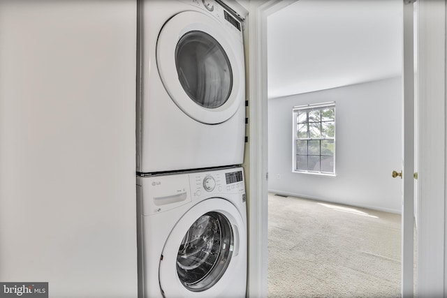 washroom with carpet floors, stacked washer and dryer, and laundry area