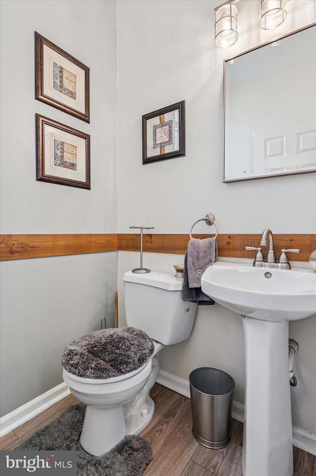 half bath with backsplash, toilet, and wood finished floors