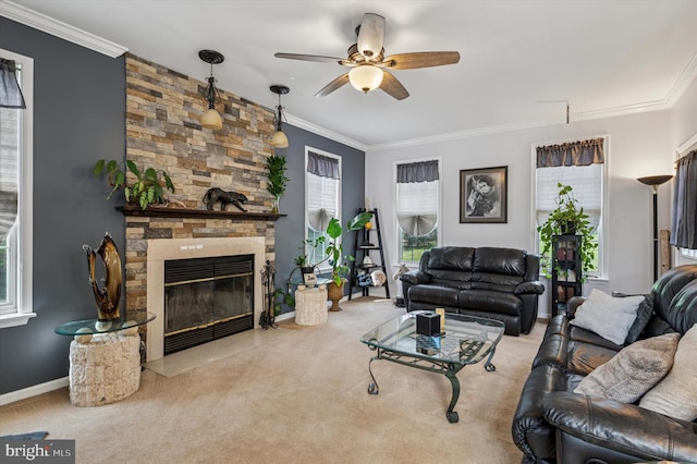 living area with ceiling fan, a stone fireplace, crown molding, carpet floors, and baseboards