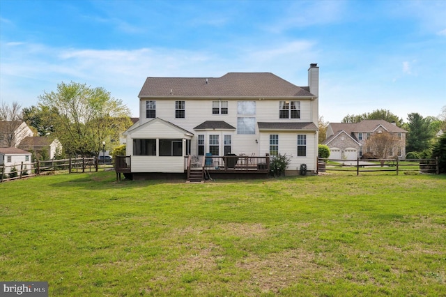 rear view of house featuring a chimney, a deck, a sunroom, a fenced backyard, and a yard