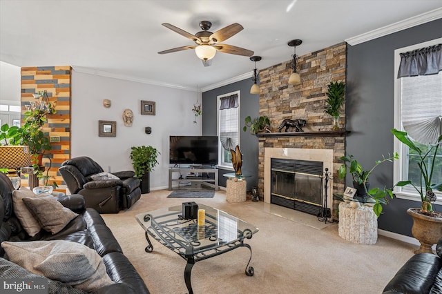 living area featuring ceiling fan, a stone fireplace, baseboards, ornamental molding, and carpet flooring