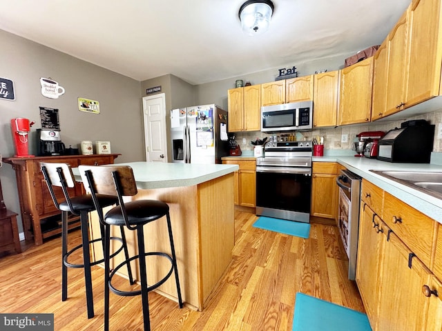 21 Holmes Dr, Charles Town, WV 25414 - kitchen with light countertops, light wood-style flooring, appliances with stainless steel finishes, and a kitchen breakfast bar