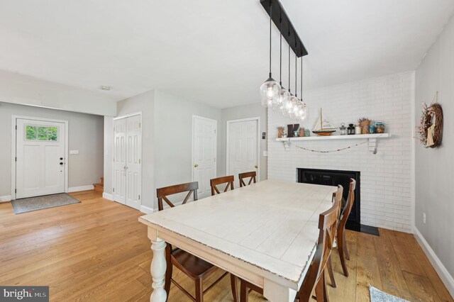 dining room featuring baseboards, light wood-style floors, and a fireplace